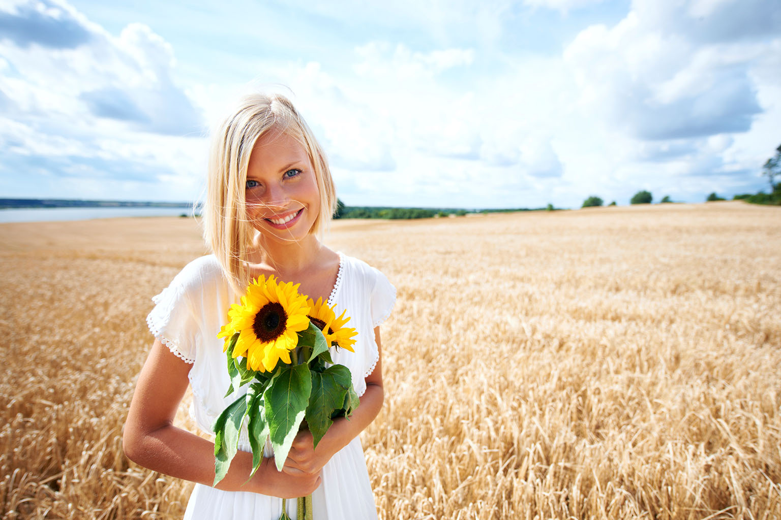 Frau mit Sonnenblumen auf einem Weizenfeld
